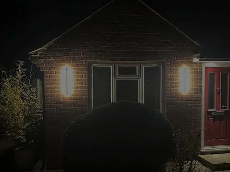 Wall lights illuminating the front of a house at night